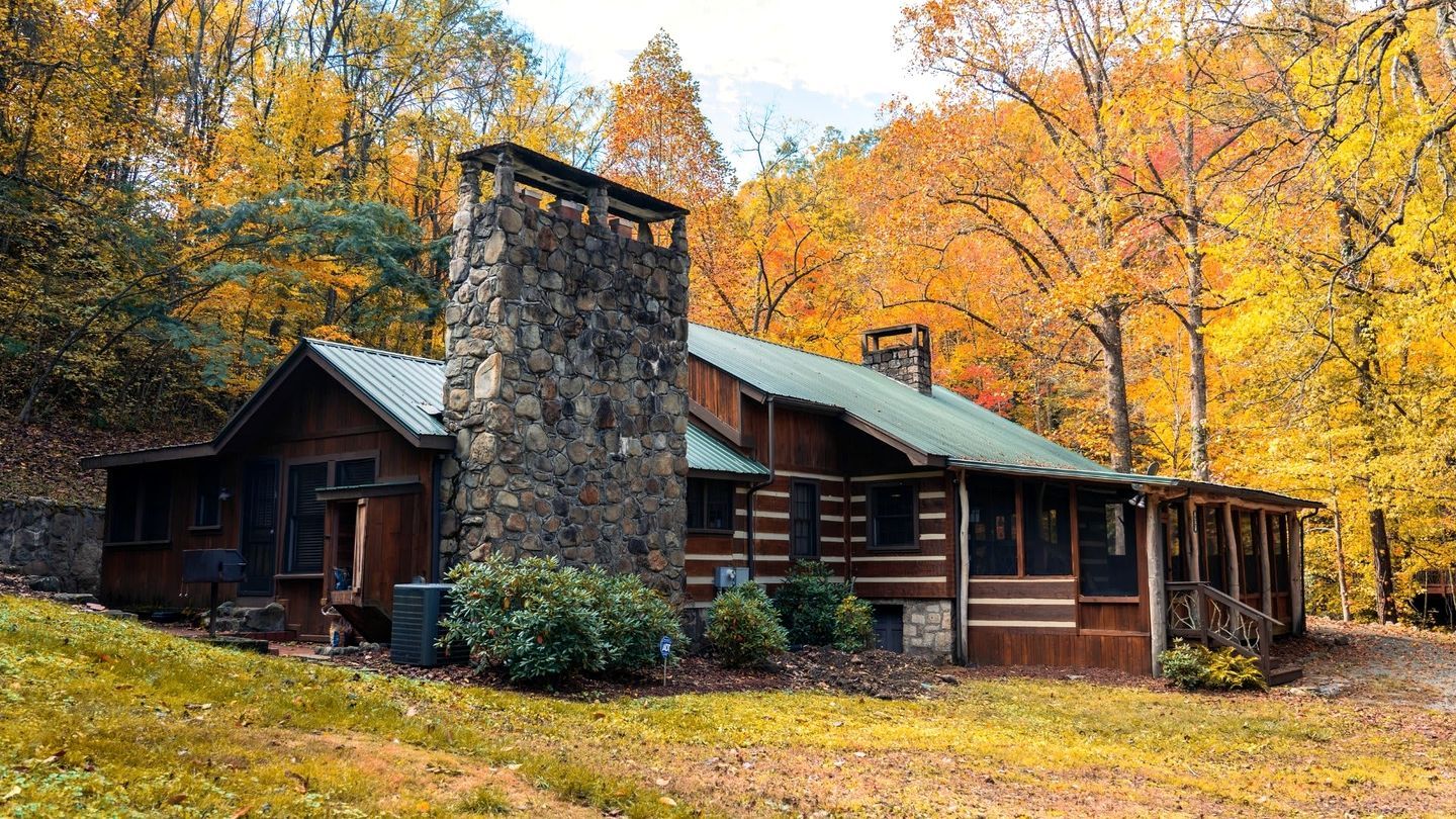 Eine rustikale Holzhütte mit einem Steinkamin, Holzfassade und einer Veranda.