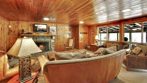 A cozy cabin interior with a fireplace, leather sofa, and a television mounted on the wall. - Exclusive Retreat: Unique Cabin Getaway Along Norton Creek in Gatlinburg, TN (Gatlinburg)