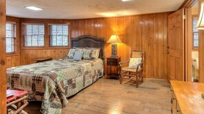 A bedroom with a bed, a chair, a nightstand, and a lamp. - Exclusive Retreat: Unique Cabin Getaway Along Norton Creek in Gatlinburg, TN (Gatlinburg)