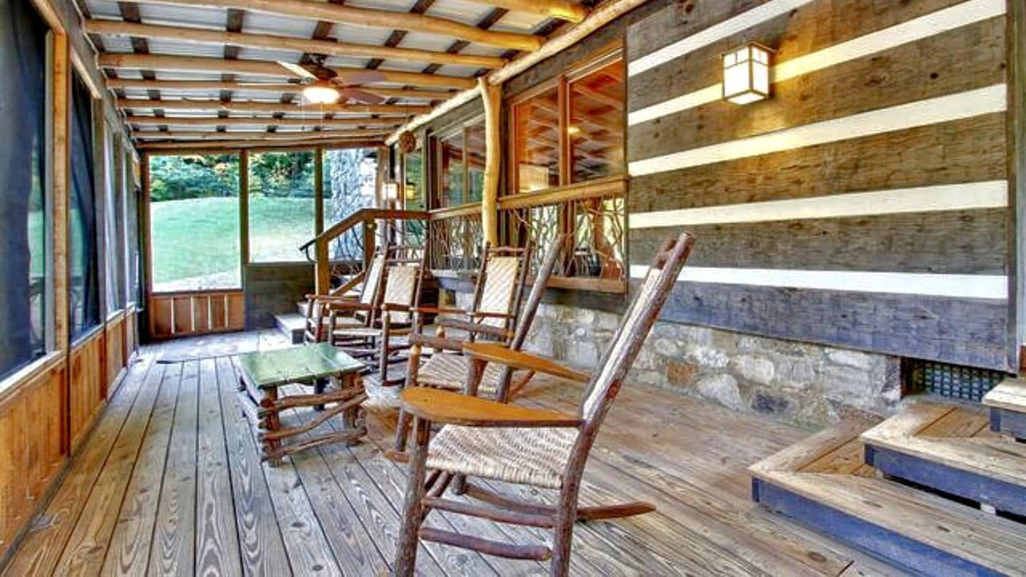 A wooden deck with outdoor seating and a stone wall.