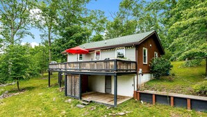 Una casa de dos pisos con un balcón de madera y un paraguas rojo.