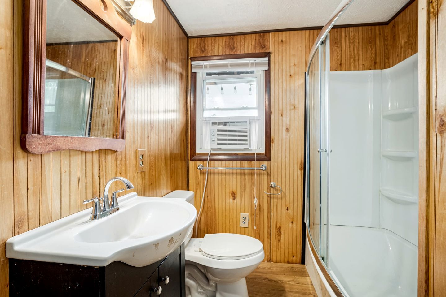 Een betegelde badkamer met een wastafel, toilet en douchecabine met glazen wanden.