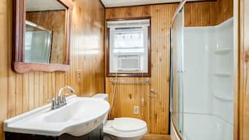 Een betegelde badkamer met een wastafel, toilet en douchecabine met glazen wanden.