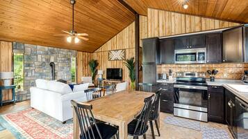 A modern kitchen with dark cabinets, stainless steel appliances, and a stone accent wall.