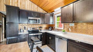 A kitchen with dark cabinets, stainless steel appliances, and a tiled backsplash.