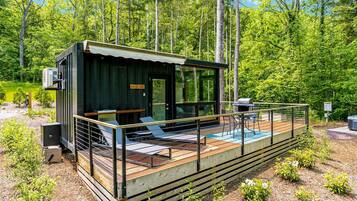 Uma cabana com deck, área de estar externa e churrasqueira.