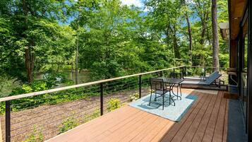 A deck with a view of a forest and a body of water.