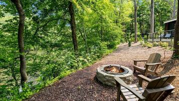 Ein runder Feuerkorb aus Stein mit zwei Adirondack-Stühlen und einem Kiesweg.