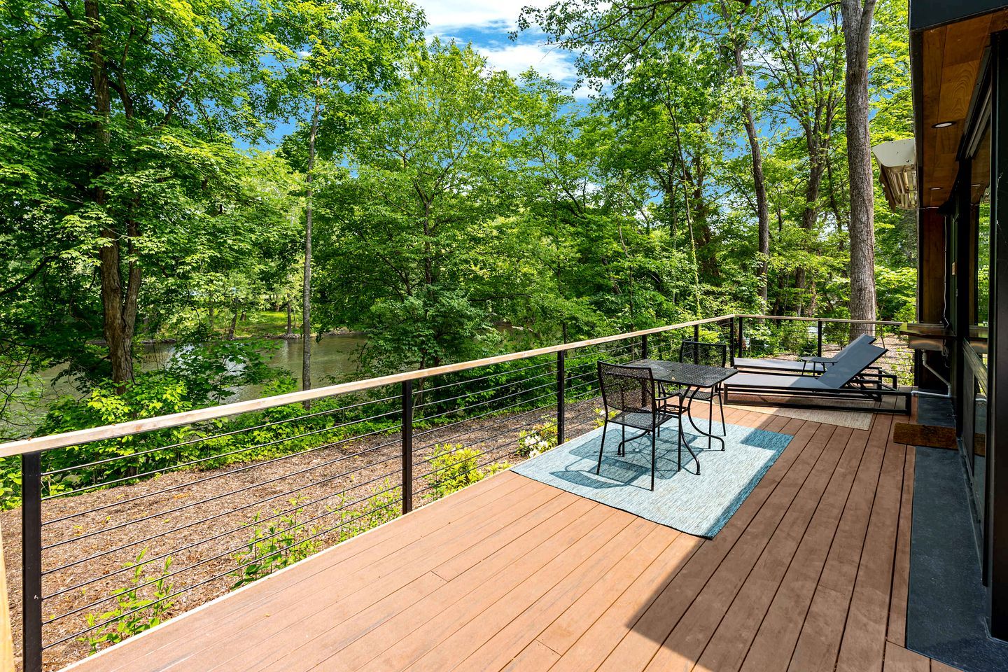 A deck with a view of a forest and a body of water.