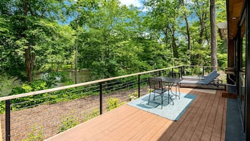 A deck with a view of a forest and a body of water.