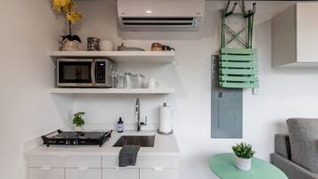 Uma cozinha moderna com micro-ondas, fogão, pia e uma pequena mesa com uma planta.