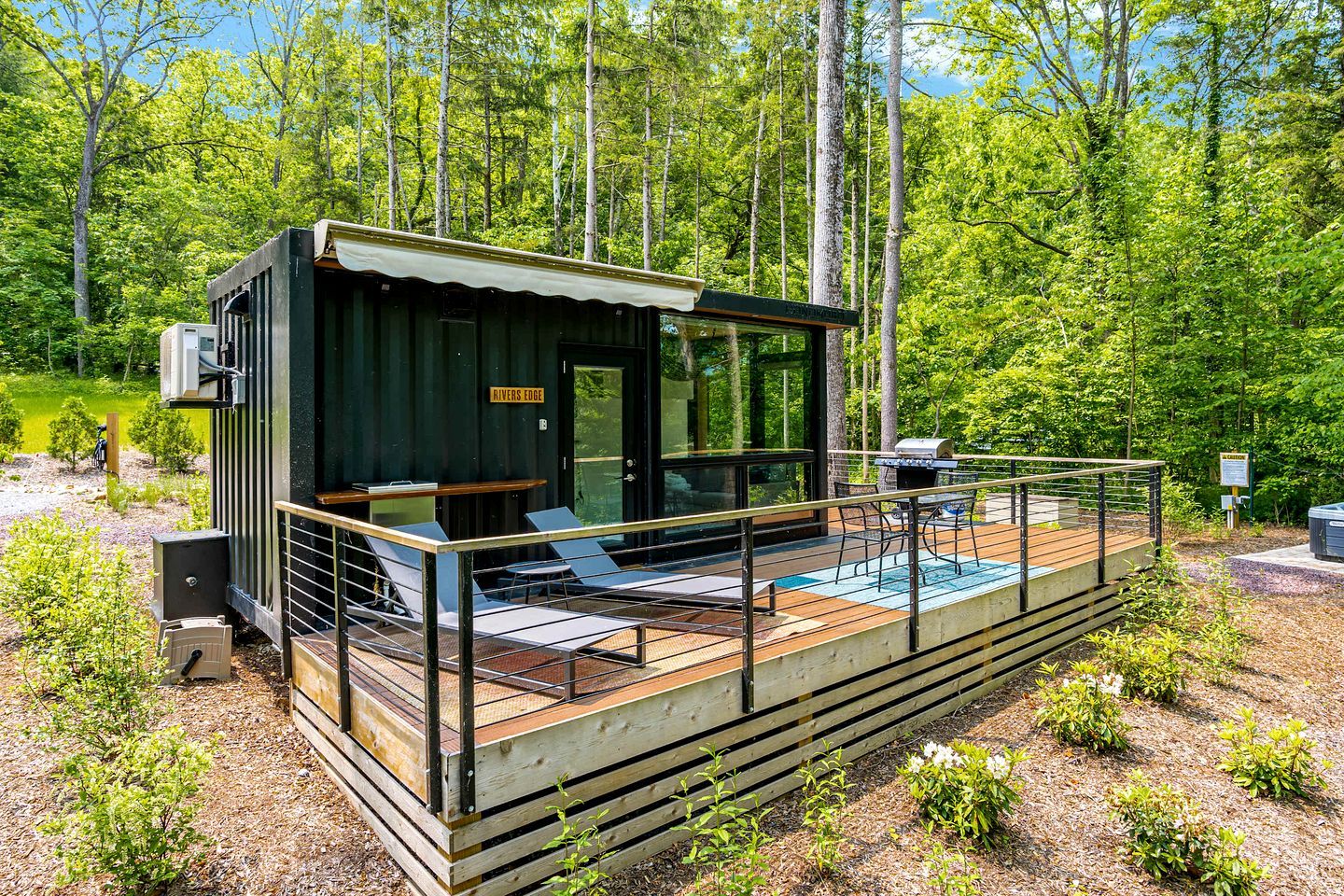 A cabin with a deck, outdoor seating, and a grill area.