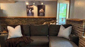 Uma sala de estar moderna com sofá modular, tapete estampado e parede de tijolos decorativa.