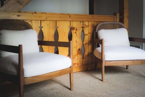 Zwei hölzerne Stühle mit weißen Kissen, ein gewobener Rücken und ein Holzkopf, der ein besonderes Design aufweist.