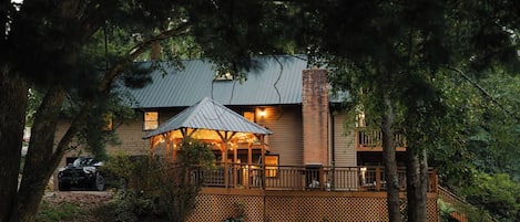 A two-story house with a wooden deck and a covered outdoor area.