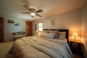 A bedroom with a bed, a ceiling fan, a window, a wall-mounted sign, and a bedside lamp. - Waterfront Lake Views w/ Hot tub in Hocking Hills (Logan)