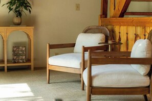 A room with two wooden chairs with white cushions, a small round table, and a bookshelf with a framed picture. - Waterfront Lake Views w/ Hot tub in Hocking Hills (Logan)