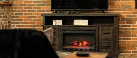 Una chimenea de ladrillo con un televisor encima y un letrero en la repisa.