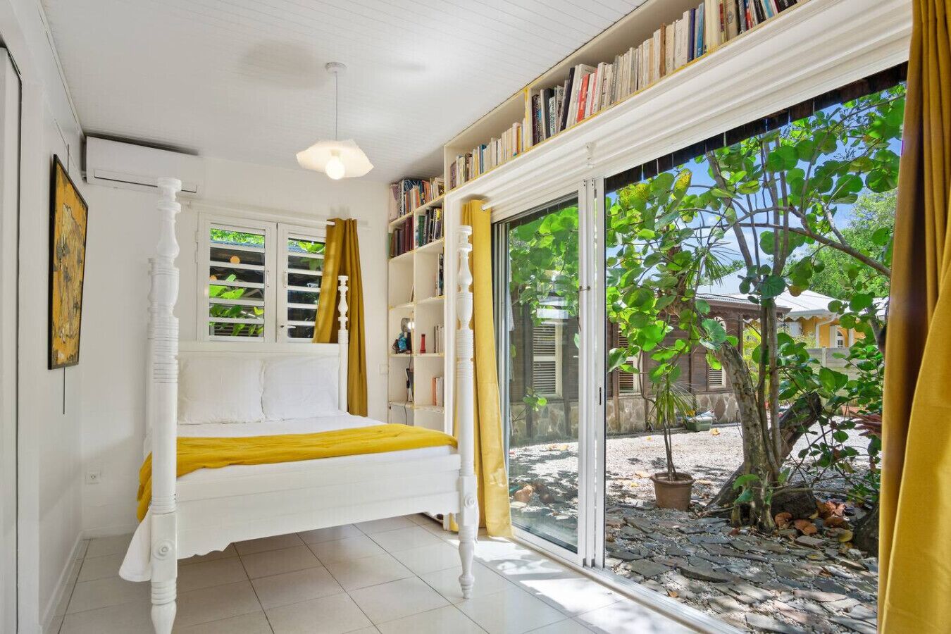 Une chambre à coucher avec un lit, une bibliothèque, une fenêtre avec des rideaux et une vue sur l’extérieur.