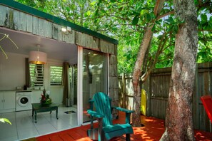 A covered outdoor area with a dining table, chairs, and a washing machine. - Les Beaux Arts Bungalow (Le Diamant)