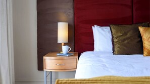 A neatly made bed with white linens, a wooden bedside table with a lamp, and a red headboard. - Tranquil Vacation Rental with Amazing Lake Views and Hiking Trails in Daylesford, Victoria (Daylesford)
