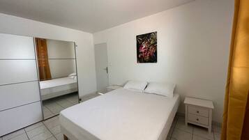 A bedroom with a large bed, a wardrobe, a bedside table, and a painting on the wall.