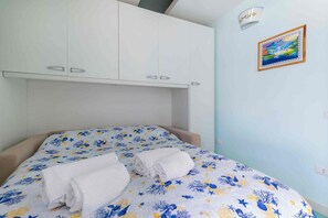 Une chambre à coucher avec un lit, deux serviettes blanches, un tableau et une armoire blanche.