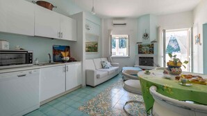 Cocina con armarios blancos, estufa y pileta. Hay un comedor con mesa y sillas.