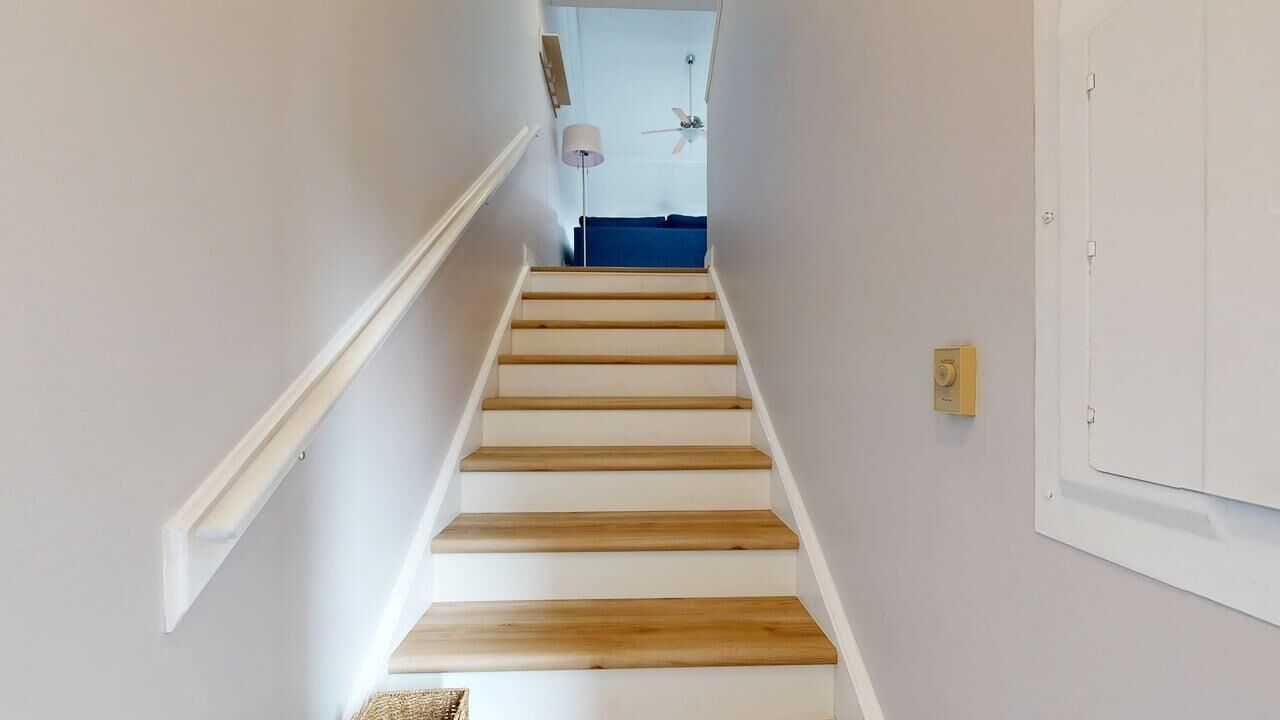 Una escalera con escalones de madera y paredes blancas.