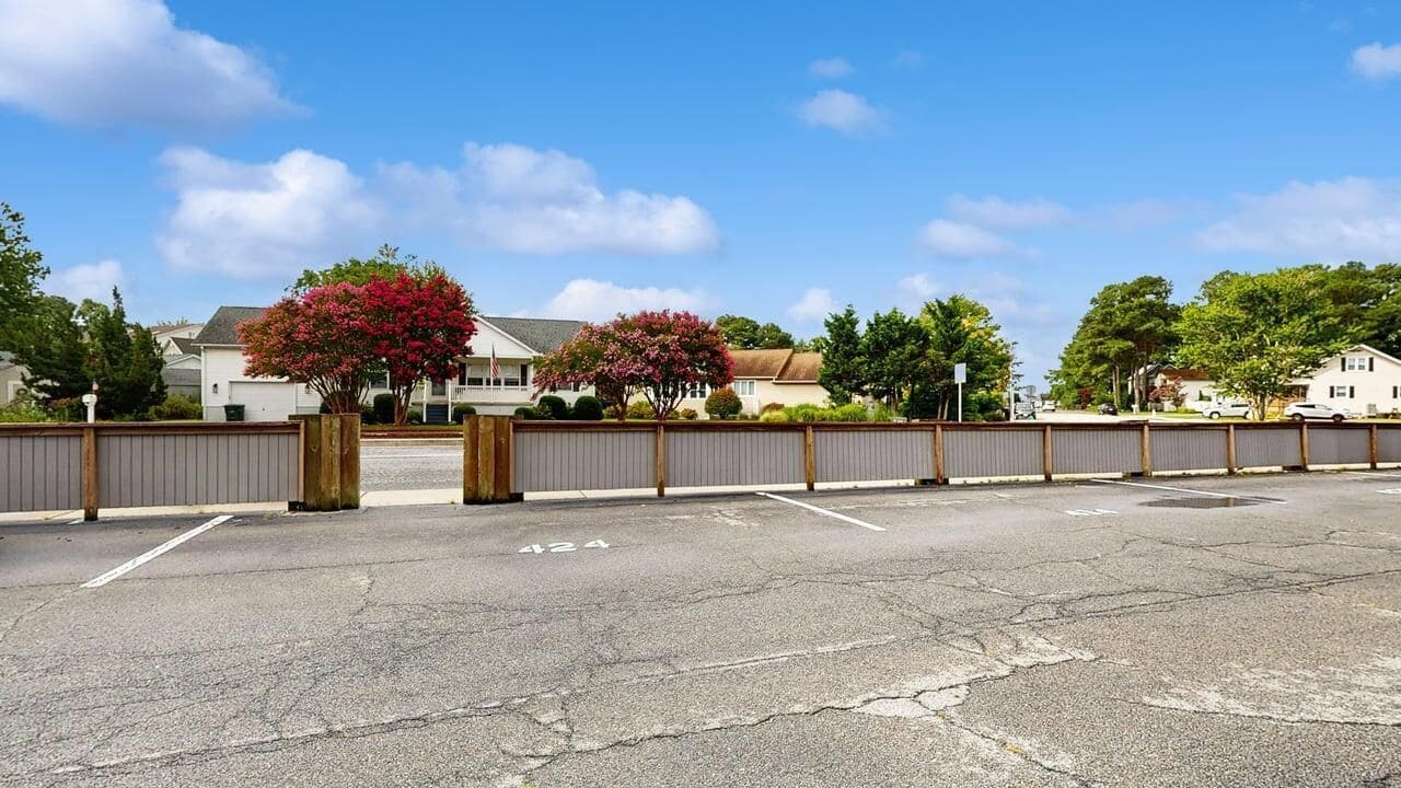 Un parking doté d’une entrée avec barrière, un ciel dégagé et des immeubles d’habitation en arrière-plan.