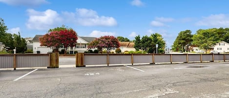 Un parking doté d’une entrée avec barrière, un ciel dégagé et des immeubles d’habitation en arrière-plan.