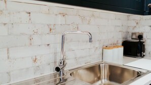 A kitchen with a stainless steel sink, a white tiled backsplash, and a toaster on the countertop. - 3 Nottingham Apts + Castle Views & City Centre (Nottingham)