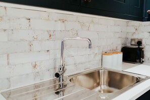 A kitchen with a stainless steel sink, a white tiled backsplash, and a toaster on the countertop. - 3 Nottingham Apts + Castle Views & City Centre (Nottingham)