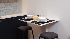A kitchen with a white countertop, black stools, and framed artwork on the wall. - 3 Nottingham Apts + Castle Views & City Centre (Nottingham)