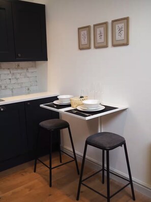 A kitchen with a white countertop, black stools, and framed artwork on the wall. - 3 Nottingham Apts + Castle Views & City Centre (Nottingham)