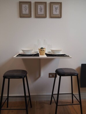 A dining table with two stools, a basket, and a set of bowls and glasses. - 3 Nottingham Apts + Castle Views & City Centre (Nottingham)