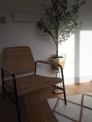 A wicker chair with a metal frame, a potted plant, and a framed quote on the wall. - 3 Nottingham Apts + Castle Views & City Centre (Nottingham)