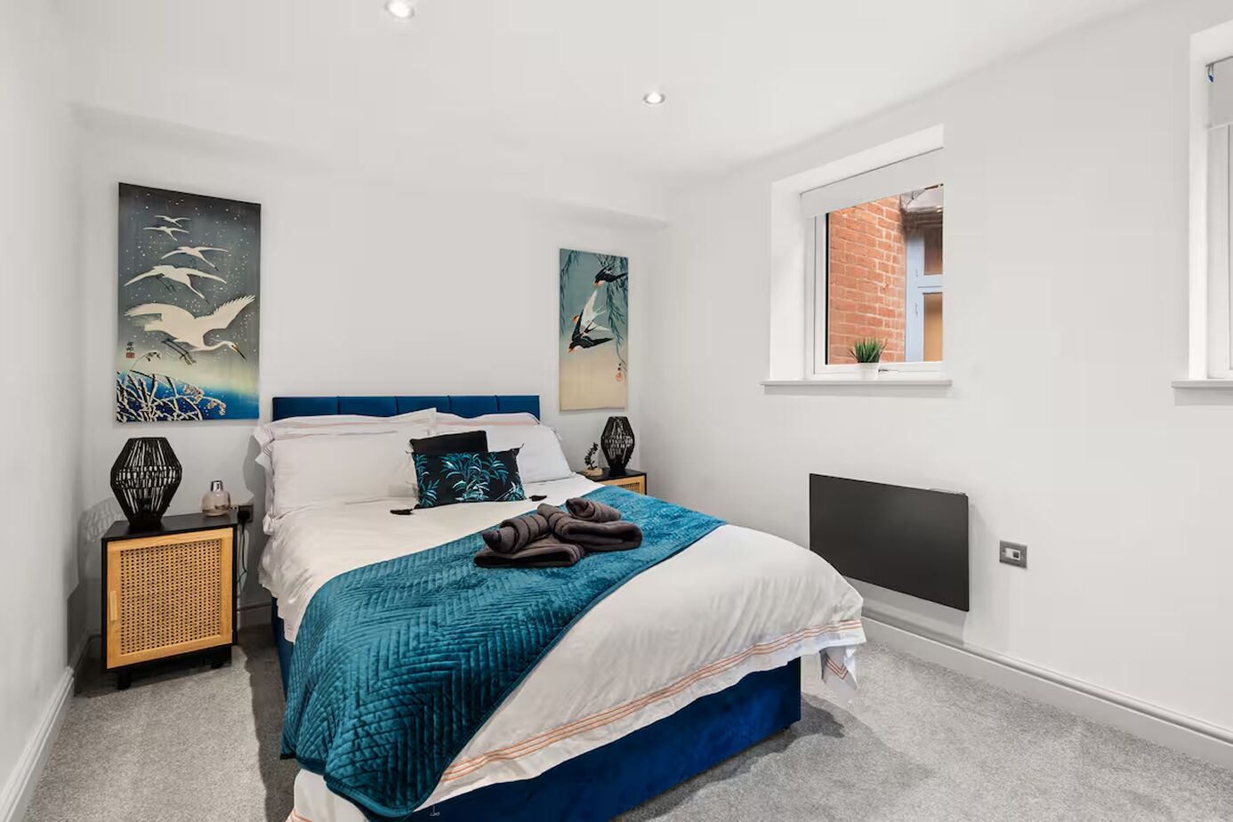 A modern bedroom with a bed, artwork, a window, and a television.