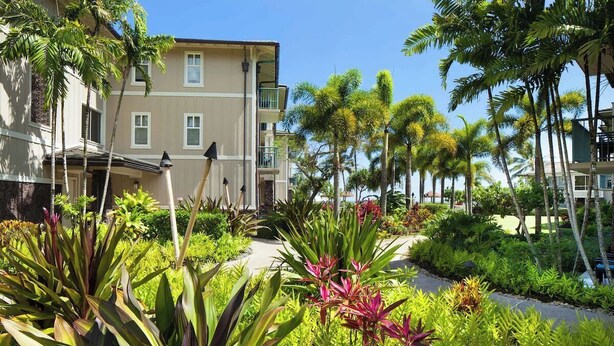 A hotel with a multi-story structure, a landscaped garden with tropical plants, and a clear sky. - Princeville One Bedroom Villa Resort w/ Amenities (Princeville)