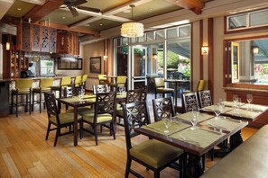 A restaurant with wooden flooring, multiple tables and chairs, and a bar area. - Princeville One Bedroom Villa Resort w/ Amenities (Princeville)