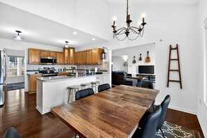 Une cuisine moderne avec des meubles en bois, un îlot central et un coin repas doté d’une grande table en bois.