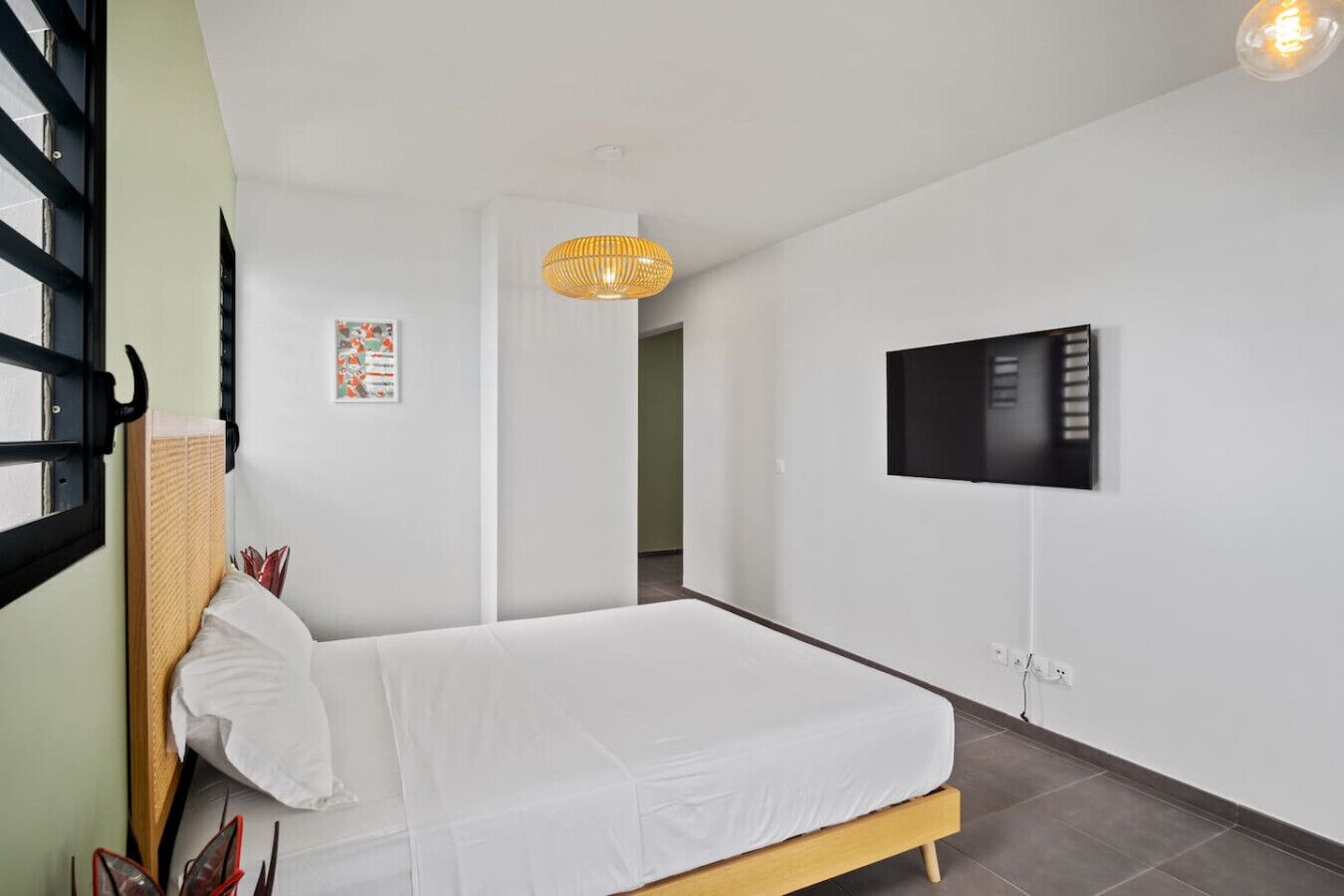Ein Schlafzimmer mit einem Bett, einem an der Wand montierten Fernseher und einer Hängeleuchte.