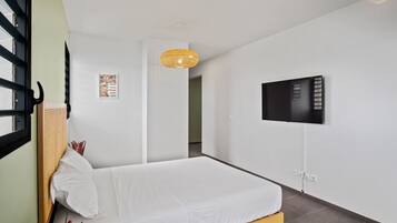 Ein Schlafzimmer mit einem Bett, einem an der Wand montierten Fernseher und einer Hängeleuchte.