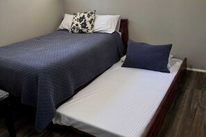 A bedroom with two beds, one with a dark quilt and the other with a white bedspread. - Charming Cottage with Foosball and Hot-tub in Big Bear Lake, California (Big Bear Lake)