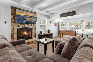 A cozy living room with a fireplace, comfortable seating, and a view of the outdoors. - Charming Cottage with Foosball and Hot-tub in Big Bear Lake, California (Big Bear Lake)