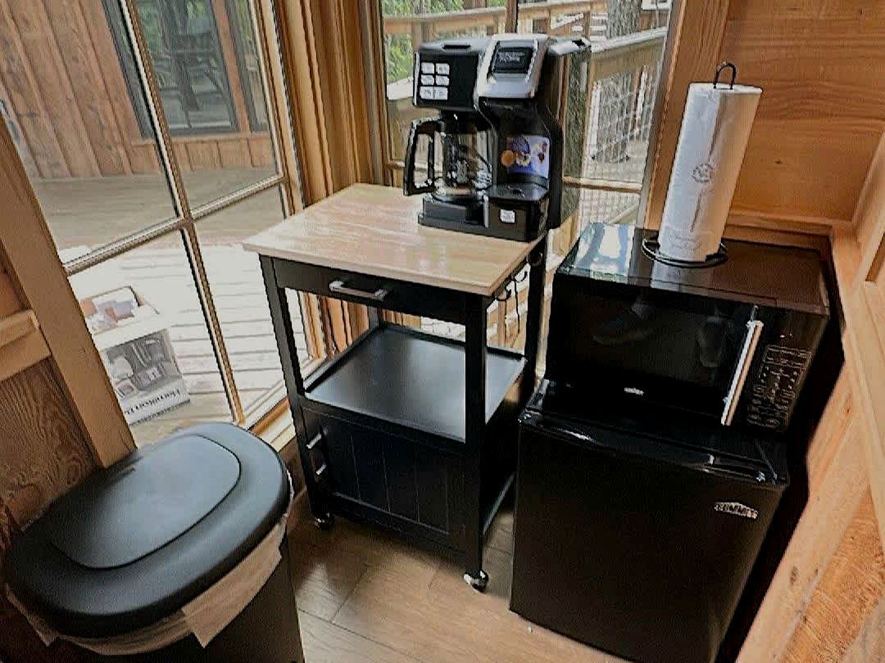 A compact kitchenette with a coffee maker, a microwave, and a trash bin.