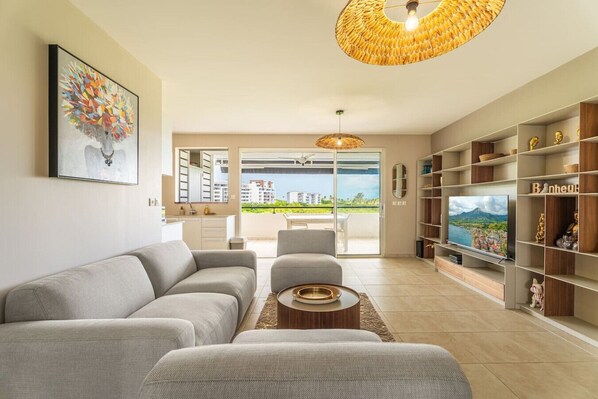 A modern living room with a sofa, a coffee table, a TV, and a bookshelf.