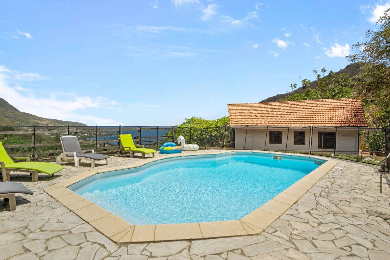 Une piscine avec des chaises longues et vue sur la mer.