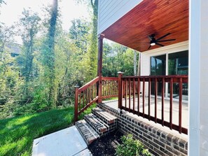 Una terraza de madera con una escalera de ladrillo que lleva a una casa con puerta de vidrio.