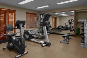 Ein Fitnessstudio mit Laufbändern, Krafttrainingsgeräten und einer Spiegelwand.